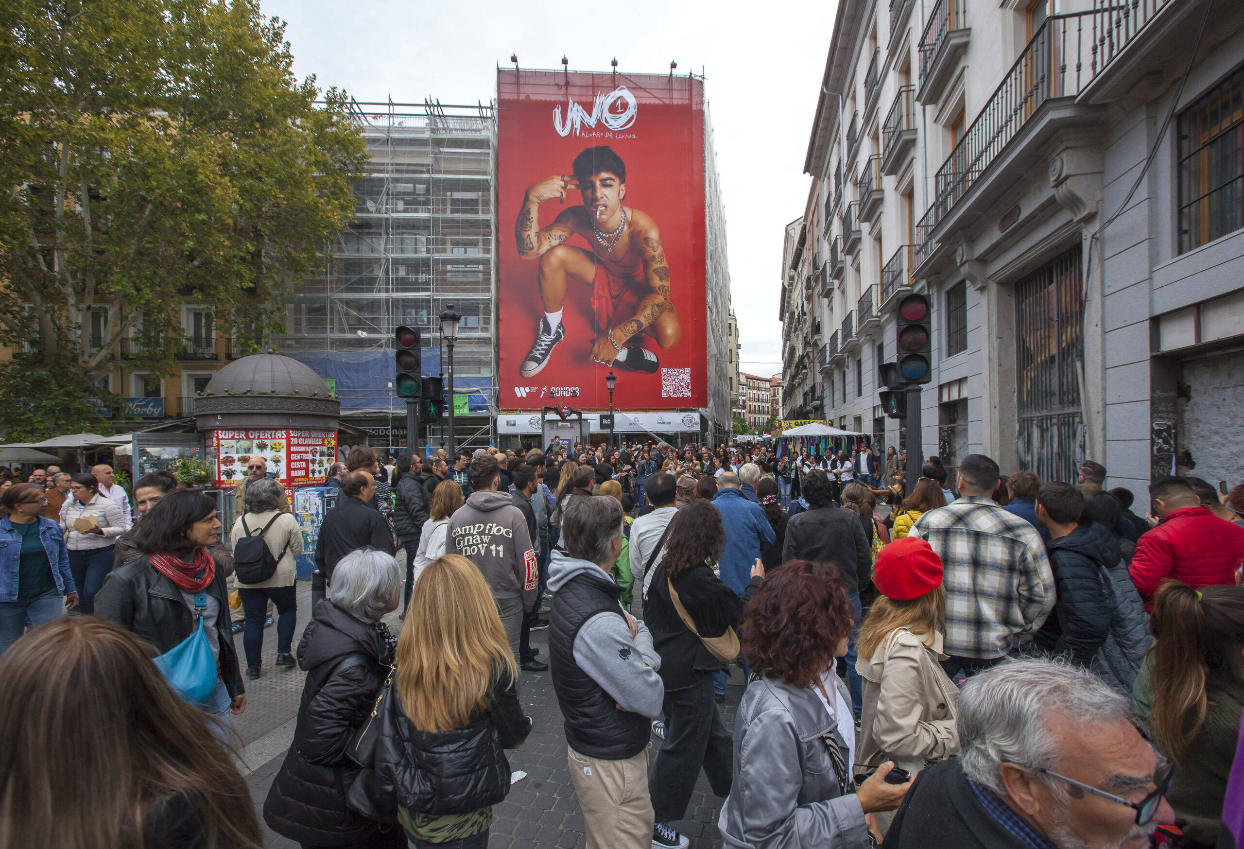 Imagen de una lona sobre el concierto de Álvaro de Luna en una calle llena de gente